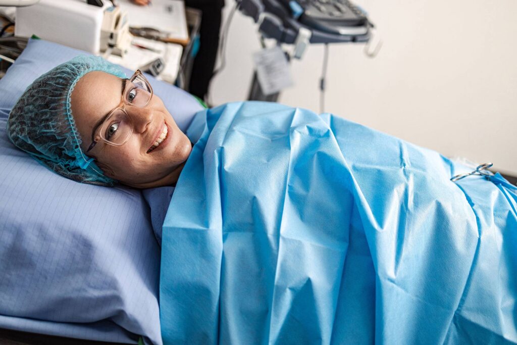 Patiente souriante et couchée sur la table d'opération prête à recevoir une microphlébectomie ambulatoire